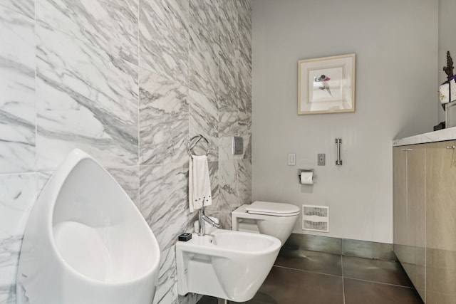 bathroom featuring toilet, tile patterned floors, tile walls, and a bidet