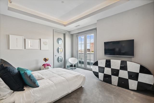 carpeted bedroom featuring french doors, access to exterior, and a tray ceiling