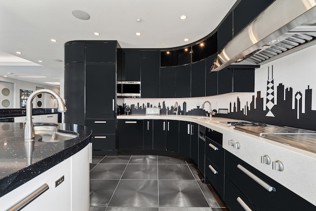 kitchen with wall chimney range hood, sink, backsplash, and dark tile patterned flooring