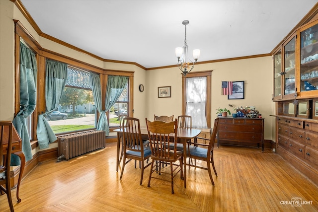 dining area featuring an inviting chandelier, ornamental molding, radiator heating unit, and light parquet floors