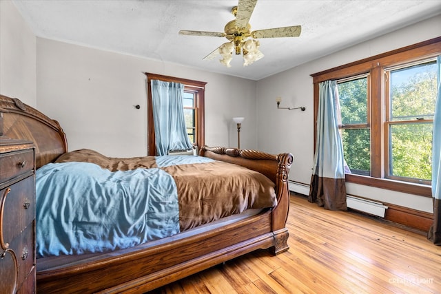 bedroom featuring ceiling fan, a baseboard radiator, light hardwood / wood-style flooring, and multiple windows