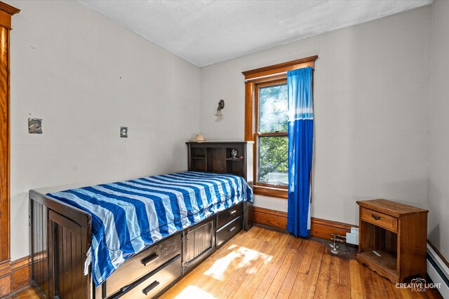 bedroom with light hardwood / wood-style flooring and a baseboard radiator