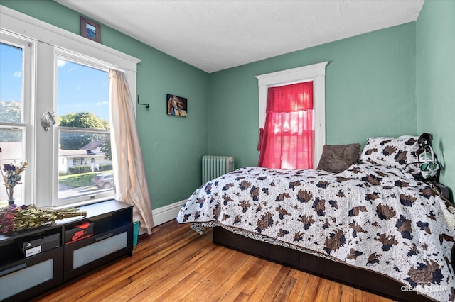 bedroom featuring radiator heating unit, light wood-type flooring, and a textured ceiling