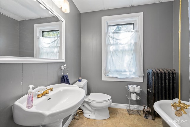 bathroom with tile patterned flooring, toilet, radiator, a bath, and sink