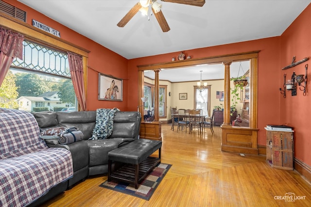 living room with ceiling fan with notable chandelier and decorative columns