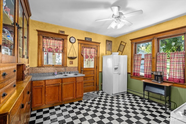 kitchen featuring ceiling fan, white refrigerator with ice dispenser, and sink