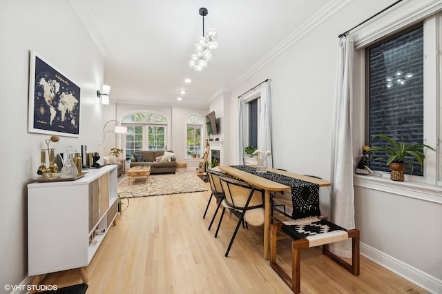 dining space featuring crown molding, light hardwood / wood-style flooring, and an inviting chandelier