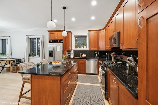 kitchen with backsplash, appliances with stainless steel finishes, a kitchen breakfast bar, a kitchen island, and decorative light fixtures