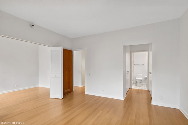 unfurnished bedroom with a closet, light hardwood / wood-style floors, and connected bathroom