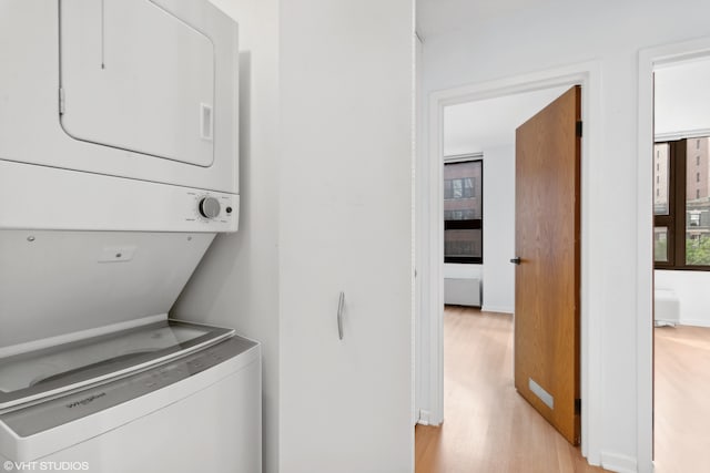 washroom with stacked washer and clothes dryer and light wood-type flooring