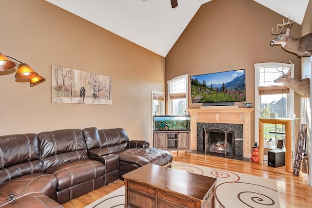 living room featuring light hardwood / wood-style floors, high vaulted ceiling, and a premium fireplace