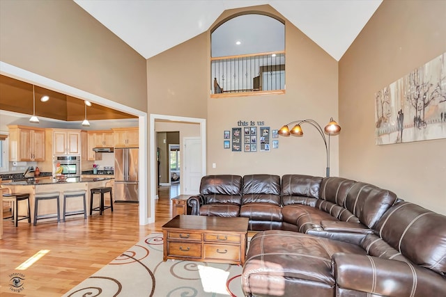 living room with high vaulted ceiling and light hardwood / wood-style flooring