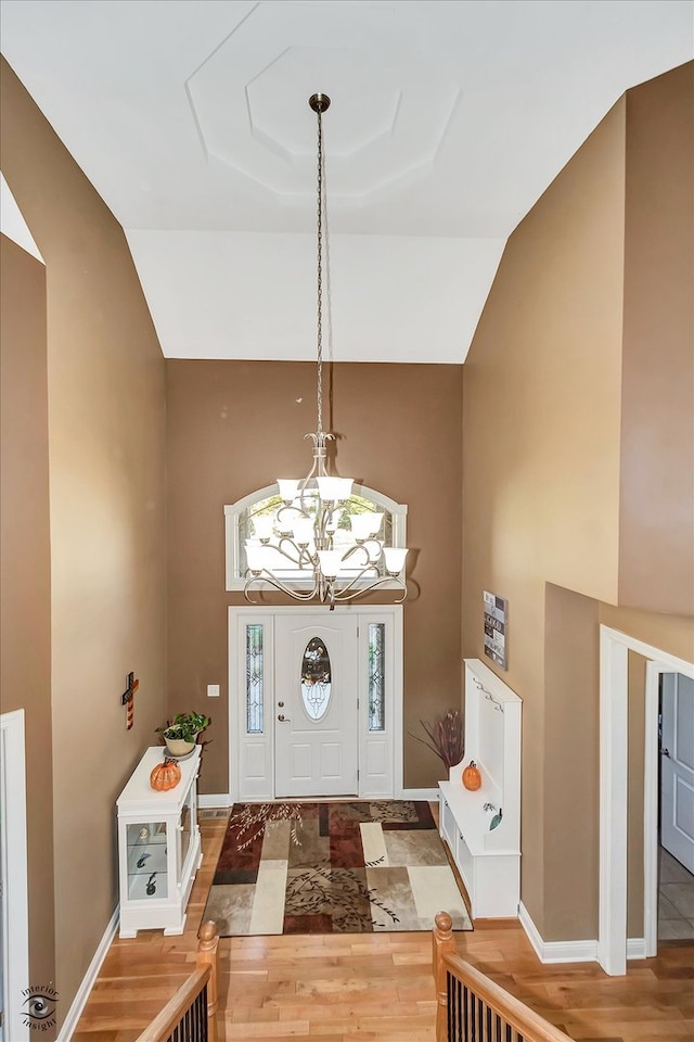 entryway with an inviting chandelier, lofted ceiling, and hardwood / wood-style floors