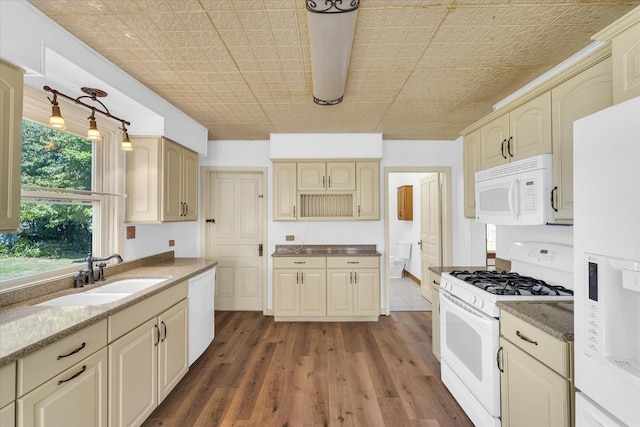 kitchen with dark hardwood / wood-style floors, white appliances, sink, cream cabinets, and stone countertops