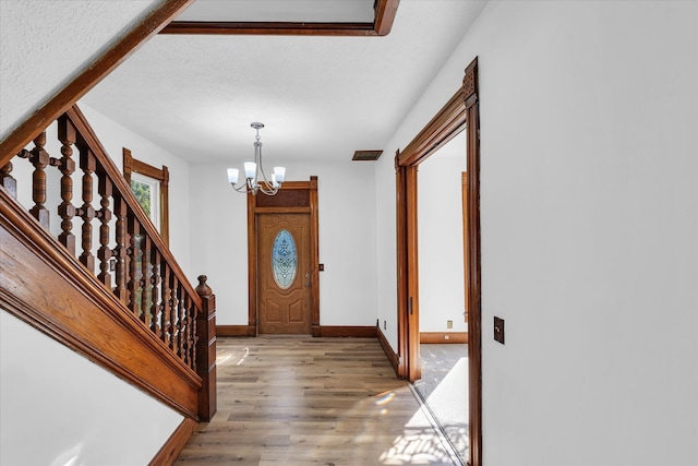 entryway with a textured ceiling, a chandelier, and hardwood / wood-style floors