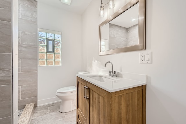 bathroom featuring vanity, toilet, and tiled shower