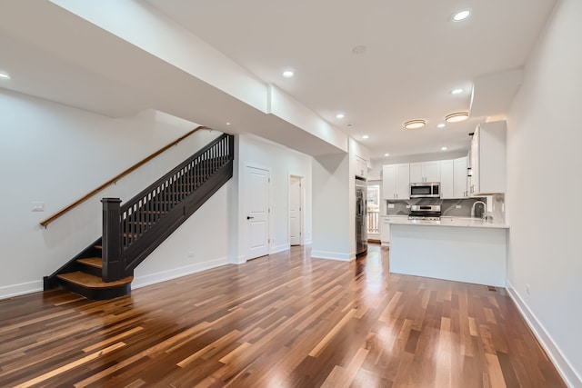 unfurnished living room featuring dark wood-type flooring and sink