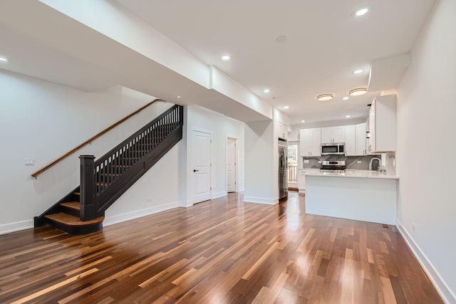 8513 S Maryland Ave, Chicago, IL 60619 - unfurnished living room with dark wood-style flooring, recessed lighting, a sink, and stairs