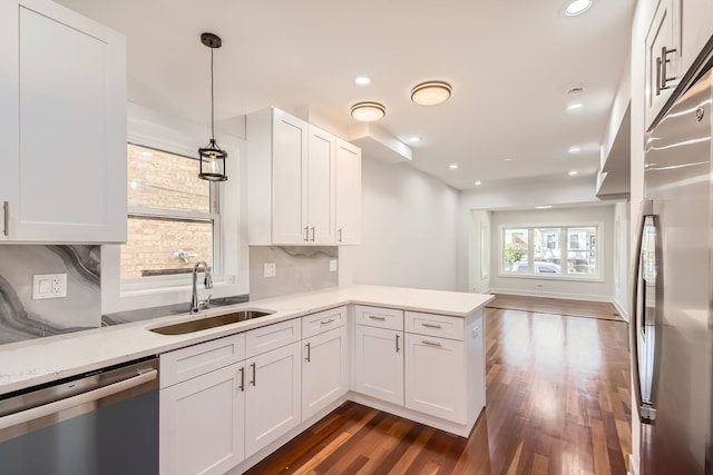 kitchen with pendant lighting, sink, white cabinetry, kitchen peninsula, and appliances with stainless steel finishes