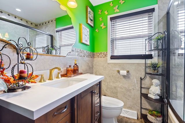 bathroom featuring walk in shower, vanity, tile walls, and toilet