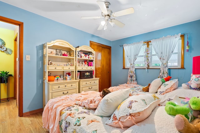 bedroom with a closet, light hardwood / wood-style flooring, and ceiling fan