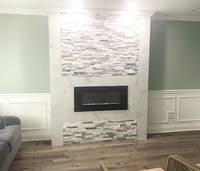 interior details with crown molding, hardwood / wood-style floors, and a tile fireplace