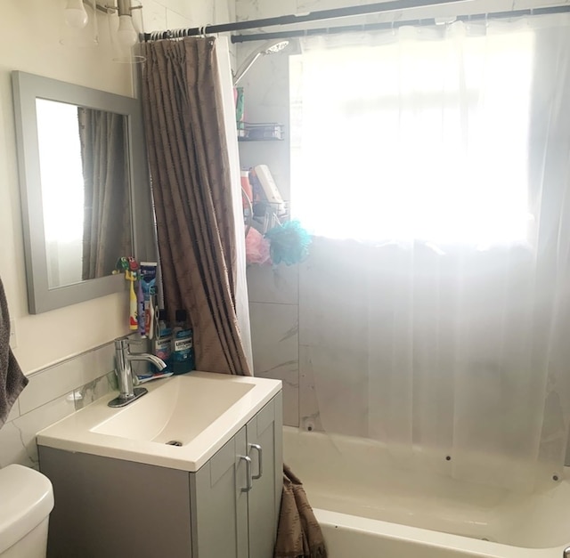 full bathroom featuring vanity, shower / bath combo with shower curtain, and toilet