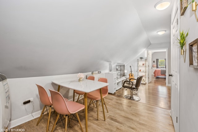 dining space with lofted ceiling and light hardwood / wood-style flooring