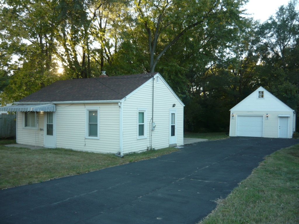 view of property exterior featuring a garage, an outdoor structure, and a lawn