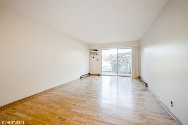 spare room with a wall mounted air conditioner, light hardwood / wood-style flooring, and a baseboard radiator