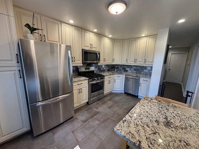 kitchen with light stone countertops, stainless steel appliances, white cabinets, and decorative backsplash