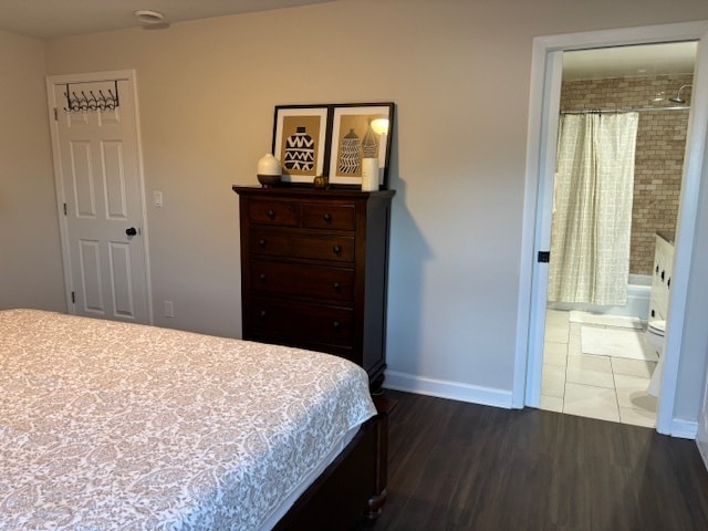 bedroom with ensuite bathroom and dark hardwood / wood-style flooring