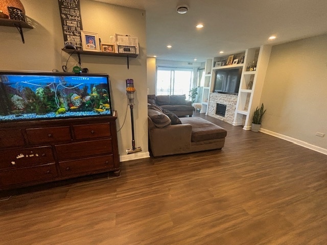 living room with built in shelves, a fireplace, and hardwood / wood-style floors