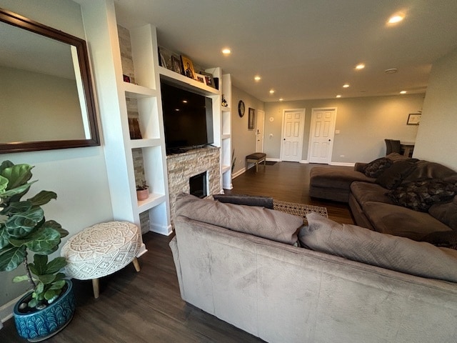 living room with a stone fireplace and dark hardwood / wood-style floors