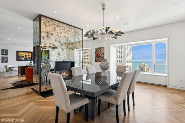 dining room featuring a tiled fireplace, light parquet floors, and a water view