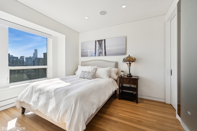 bedroom featuring hardwood / wood-style floors and a baseboard heating unit