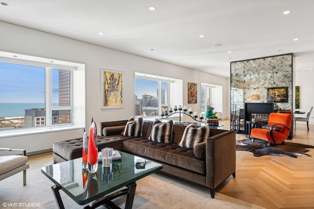 living room with a water view, light parquet flooring, and a tile fireplace