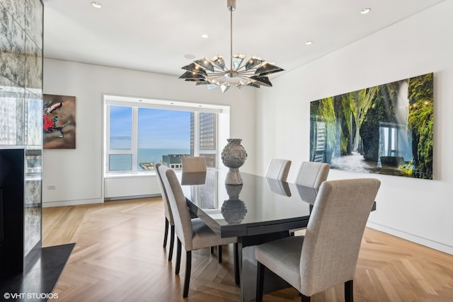 dining room with light parquet flooring, a water view, and an inviting chandelier