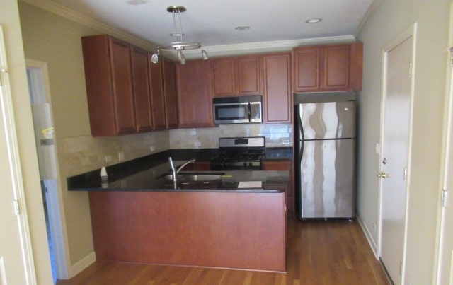 kitchen featuring appliances with stainless steel finishes, backsplash, ornamental molding, and dark hardwood / wood-style flooring