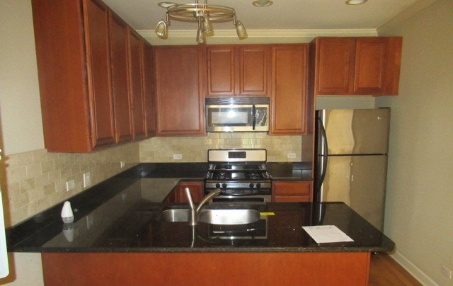 kitchen with crown molding, kitchen peninsula, stainless steel appliances, and tasteful backsplash