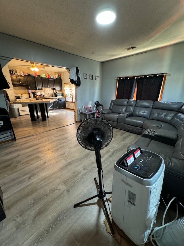 living room with wood-type flooring, a textured ceiling, and ceiling fan