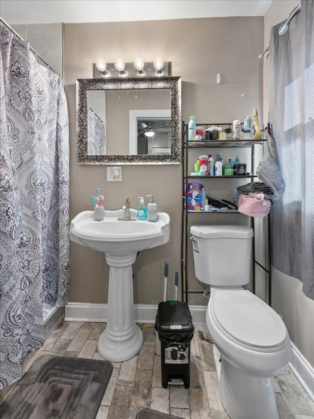 full bathroom with toilet, curtained shower, and baseboards