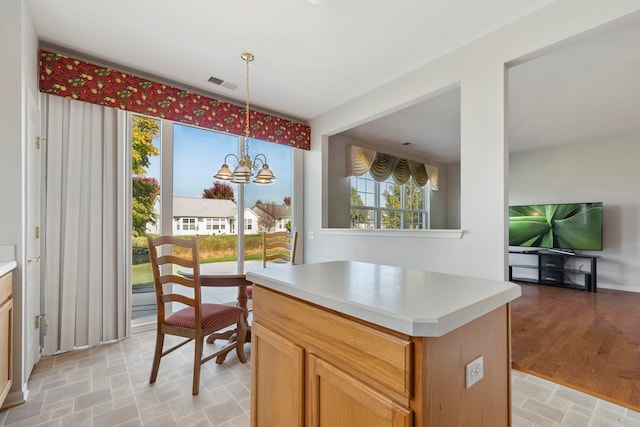 kitchen with pendant lighting, a notable chandelier, a kitchen island, and light hardwood / wood-style flooring