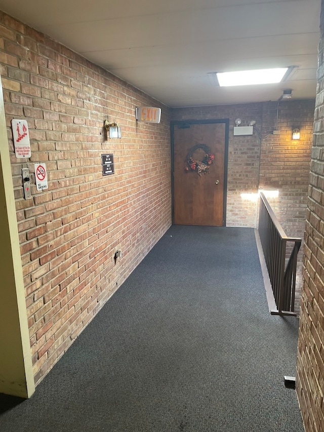 corridor with brick wall and dark colored carpet