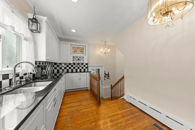 kitchen featuring light hardwood / wood-style floors, sink, white cabinets, a baseboard radiator, and decorative backsplash