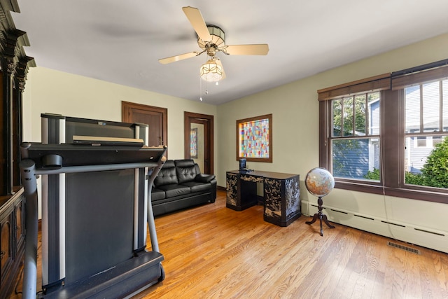 exercise area featuring a baseboard heating unit, light wood-type flooring, and ceiling fan