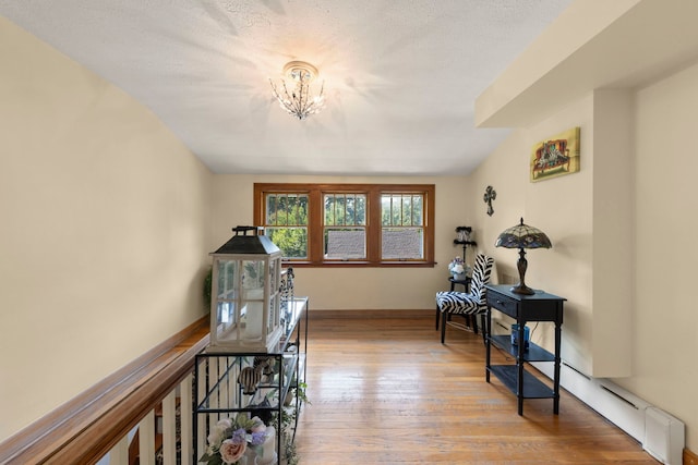 interior space with light wood-type flooring, a chandelier, and a textured ceiling