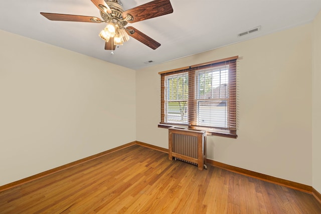 unfurnished room with ceiling fan, light hardwood / wood-style flooring, and radiator heating unit