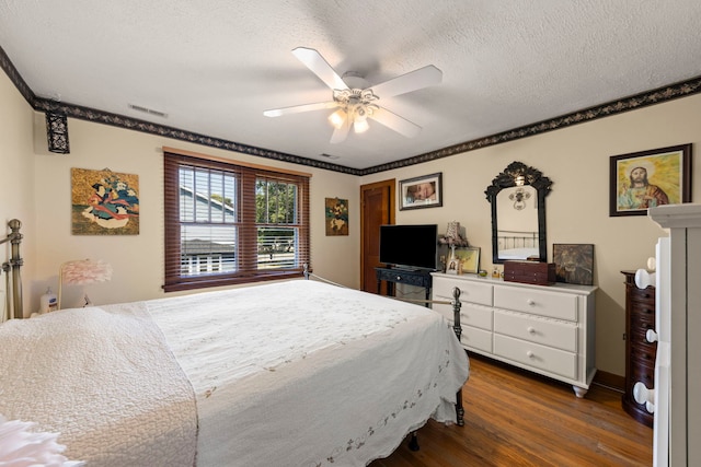 bedroom with a textured ceiling, ornamental molding, dark wood-type flooring, and ceiling fan