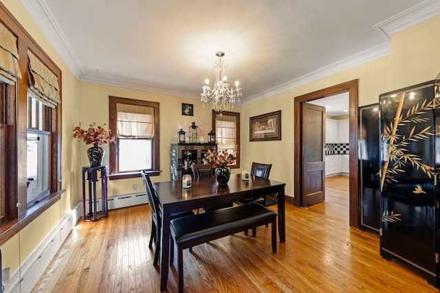 dining area with light hardwood / wood-style floors, ornamental molding, and a notable chandelier